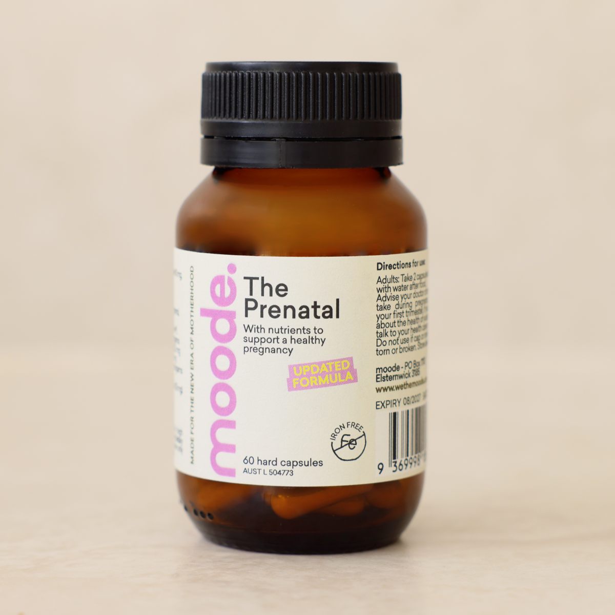 The Prenatal by moode, a 60 capsule amber glass bottle, lying beside two capsules on a cream stone surface.