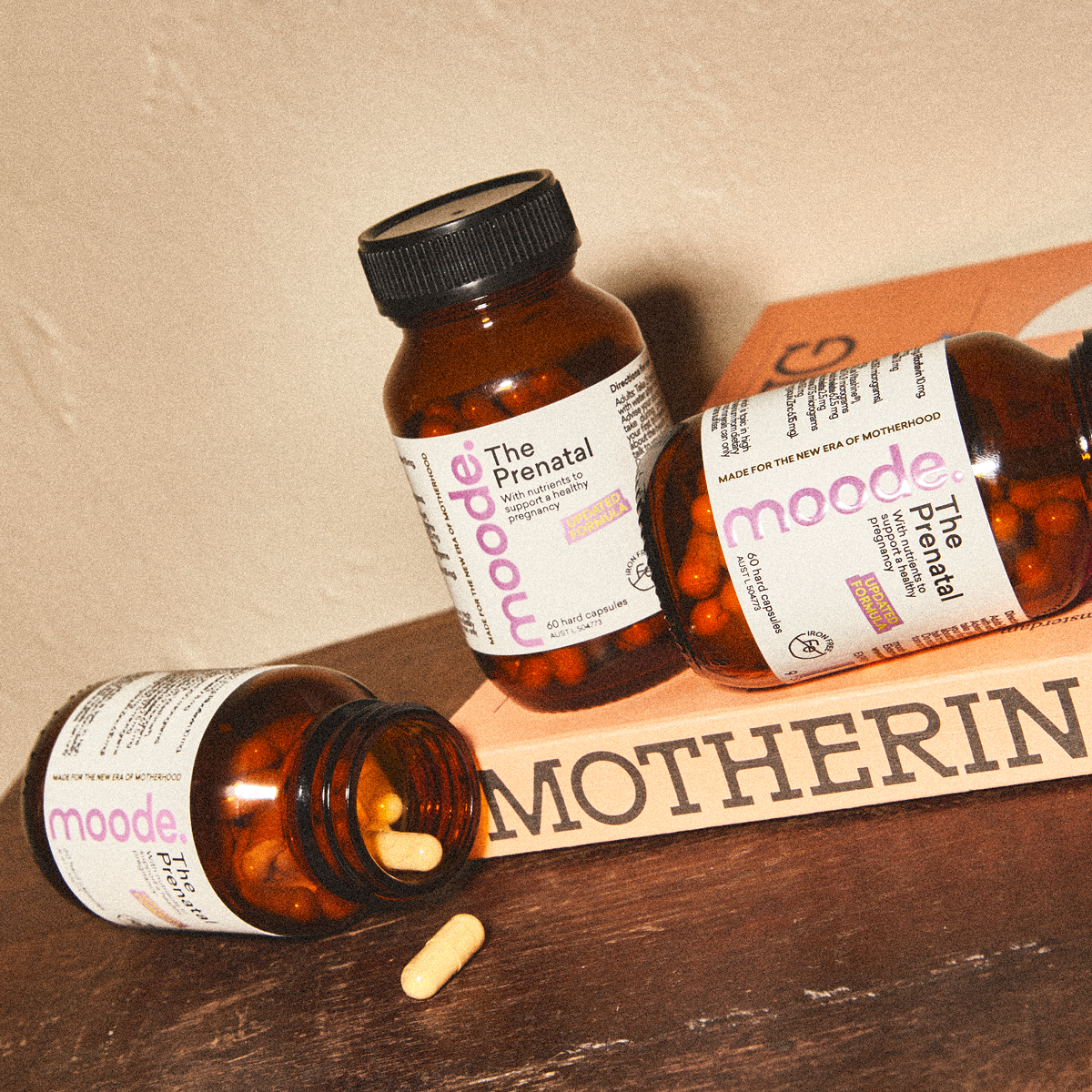 Three bottles of The Prenatal by moode together, a three month supply, on a wood surface.